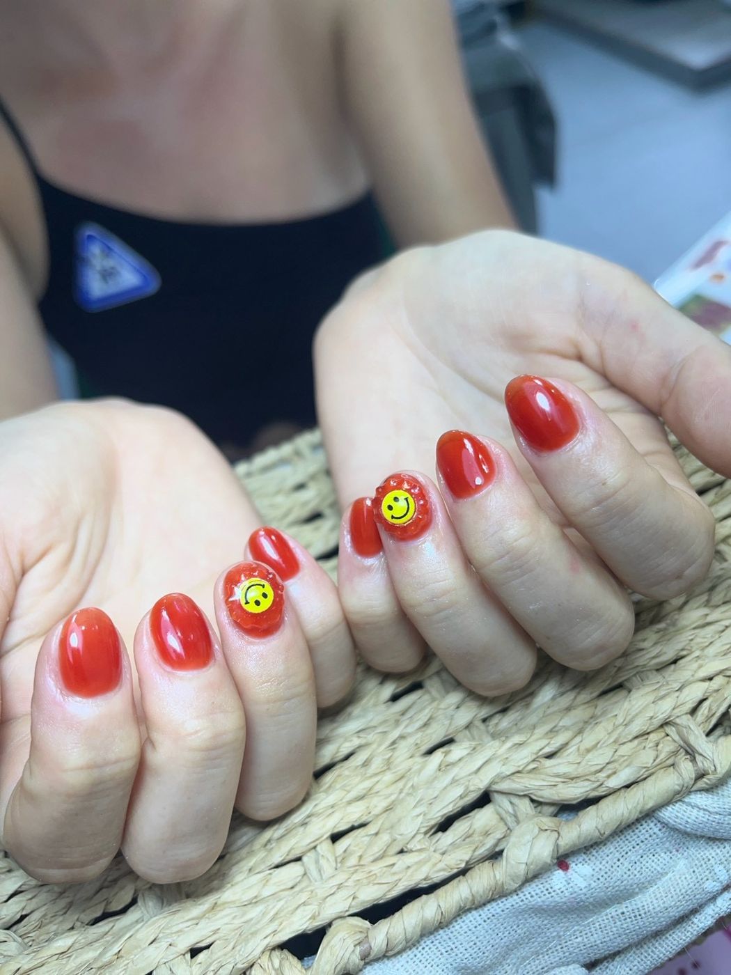 Glossy red nails with yellow smiley accents